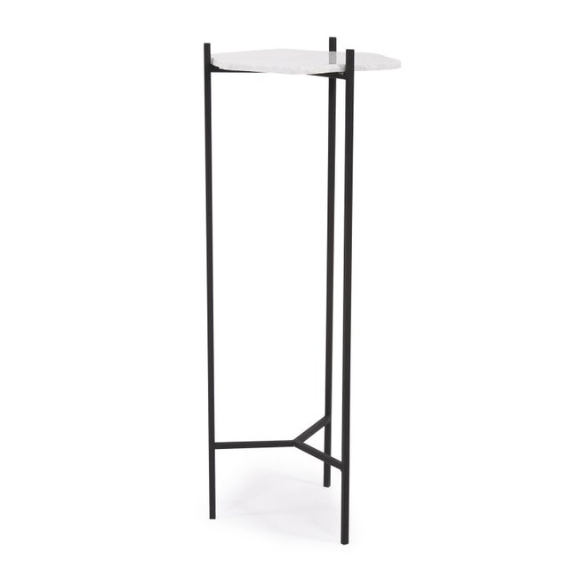 The hand quarried white marble top of the Alberta Pedestal Table is contrasted with matte black iron base to give a...