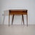 Elegant wall console raised on tall, tapered legs with brass sabots, featuring one drawer and a clear glass shelf. The...