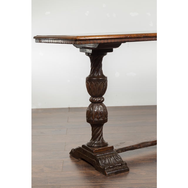 An Italian walnut console table from the early 19th century, with dentil molding, carved legs and cross stretcher. Created...