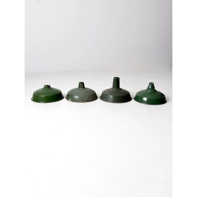 This collected set of four mid-century green enamel pendant light shades features complementary shades of green with...