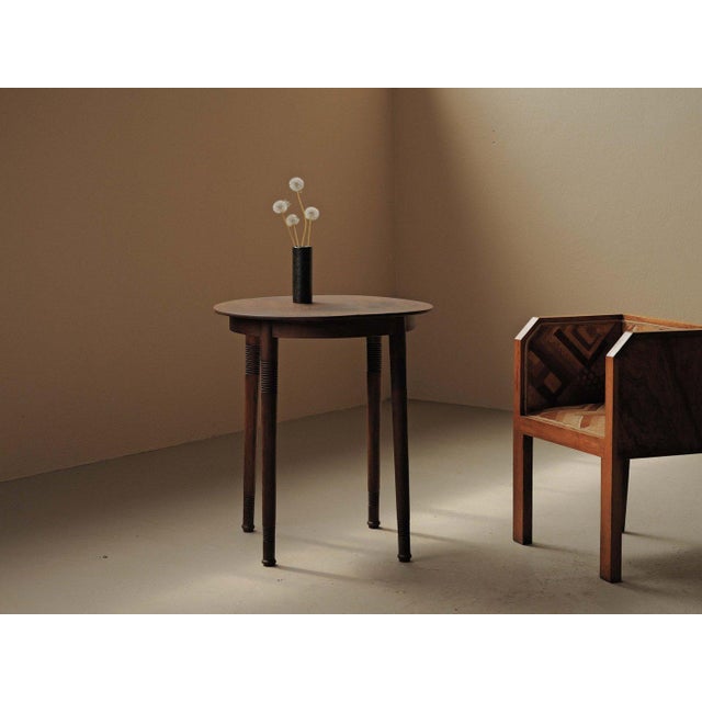 Round side table in solid wood stands on four turned, tapered legs decorated with ring motifs. The circular top, with a...