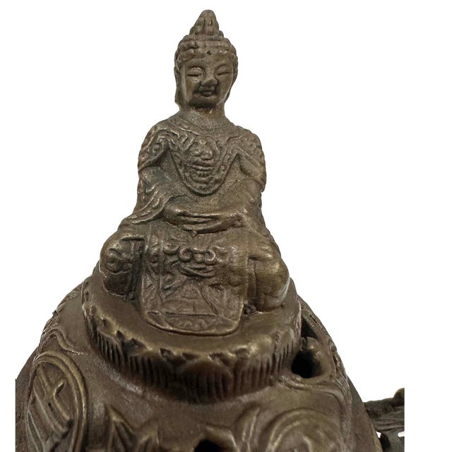 The item is a Tibetan/Chinese Buddhist tripod incense burner (censer) crafted from cast bronze. These decorative, ritual...