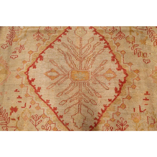 This antique Oushak rug from Turkey, dating to the late 19th century, features a spacious open field design anchored by a...