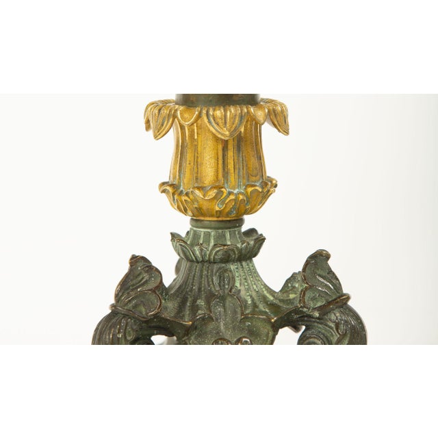 A pair of 19th century French gilt and patinated bronze candlesticks, each featuring a tapering columnar shaft in warm...