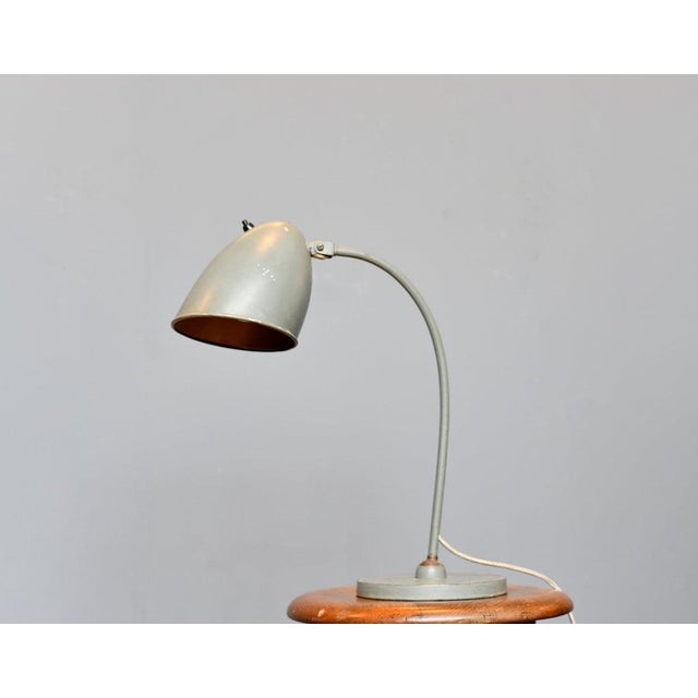 Hala Table Lamp Circa 1930s - Original grey paint - Steel shade and curved arm - Bakelite On/Off switch on the shade -...