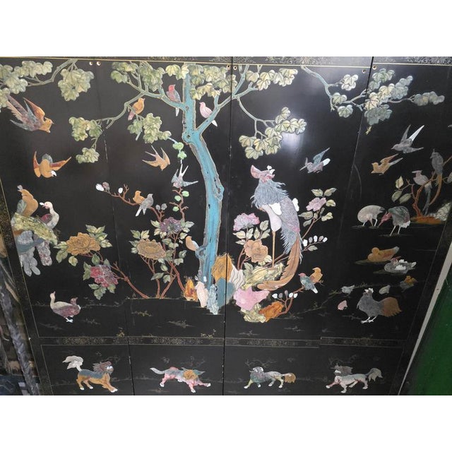 An exceptional and highly decorative Chinese folding screen dating from the early 20th century, featuring an elaborate...
