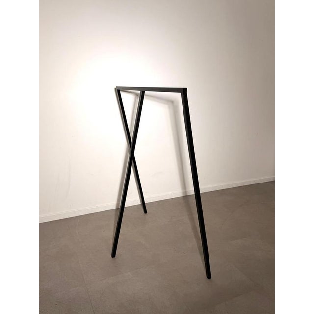 Sleek and architectural freestanding clothes rack crafted from black metal. The minimalist open-frame construction...