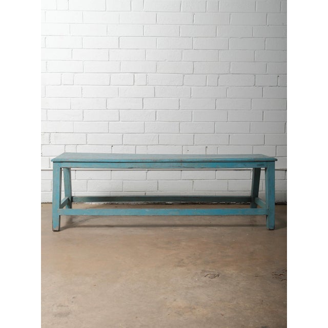 A blue painted wooden bench showcasing beautifully timeworn character and authentic surface patina. The bench features a...