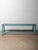 A blue painted wooden bench showcasing beautifully timeworn character and authentic surface patina. The bench features a...