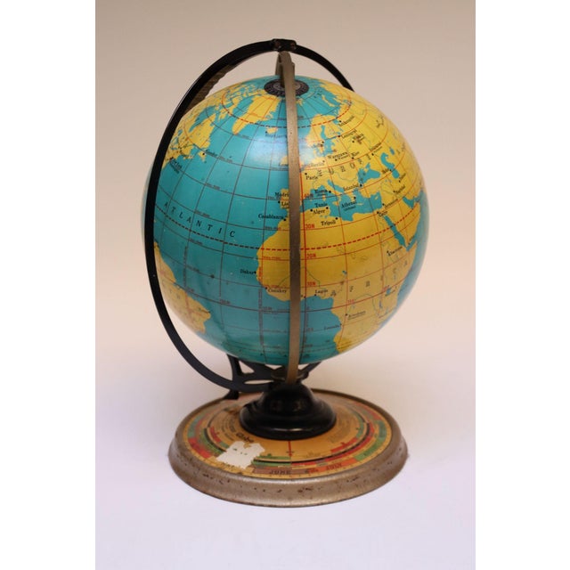 Cram's Deluxe Globe with an Automatic Daily Sun Ray Indicator supported by a metal base with lithographed seasons,...
