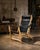 Celtia pairs an exposed solid-wood frame with a black natural Galician leather sling that forms the seat and tall...