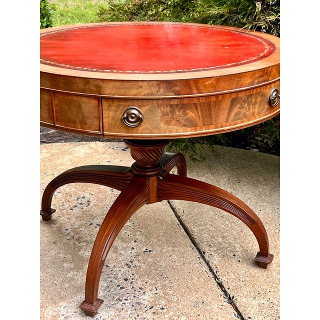 Regency-style mahogany drum table, beautifully highlighted by its striking red gilt-tooled leather inset top with a...