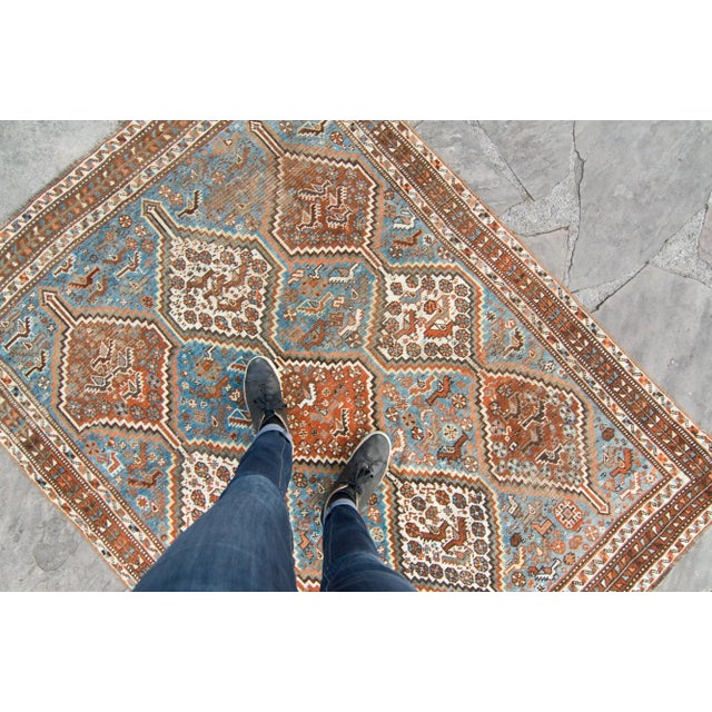 An antique rug with geometric medallions, features colors such as blue for the base, along with cinnamon, tumbleweed,...