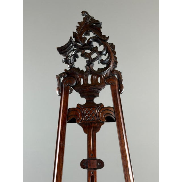 An elegant and spectacular 19th-century carved wooden painter's easel, richly decorated with plant motifs, scrolls, and...
