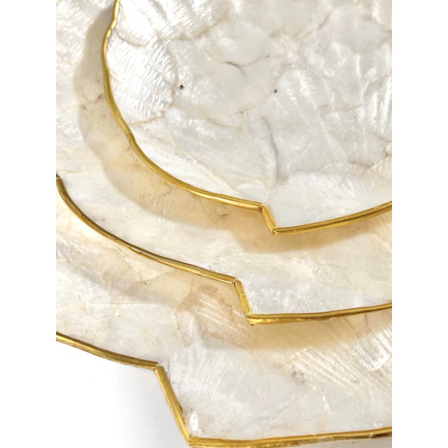 Elegant vintage capiz shell nesting trays with scalloped edges and warm brass trim, offering a soft iridescent glow....