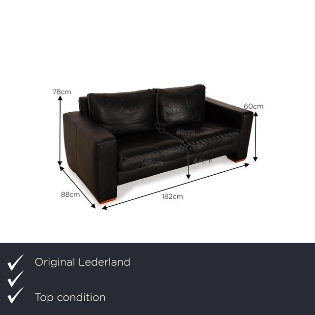 The two-seater from Lederland is covered in black genuine leather and stands on brown feet. The classic, timeless design...