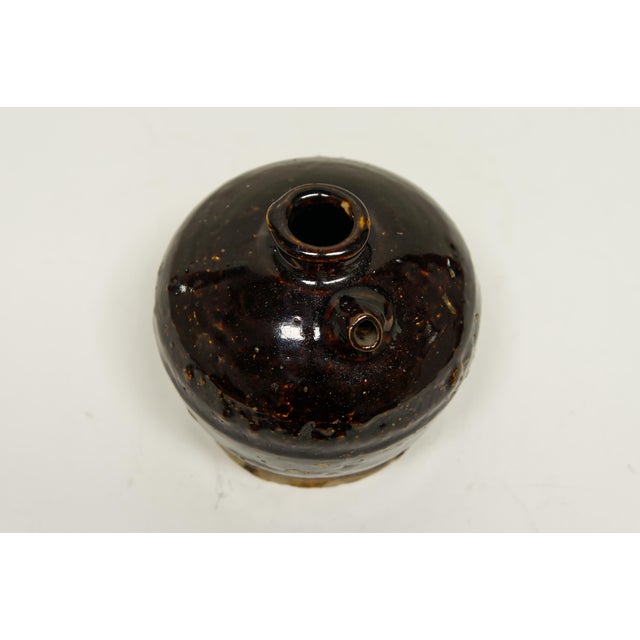 A 19th century Chinese ceramic jug with a dark brown glaze used for storing and aging vinegar.