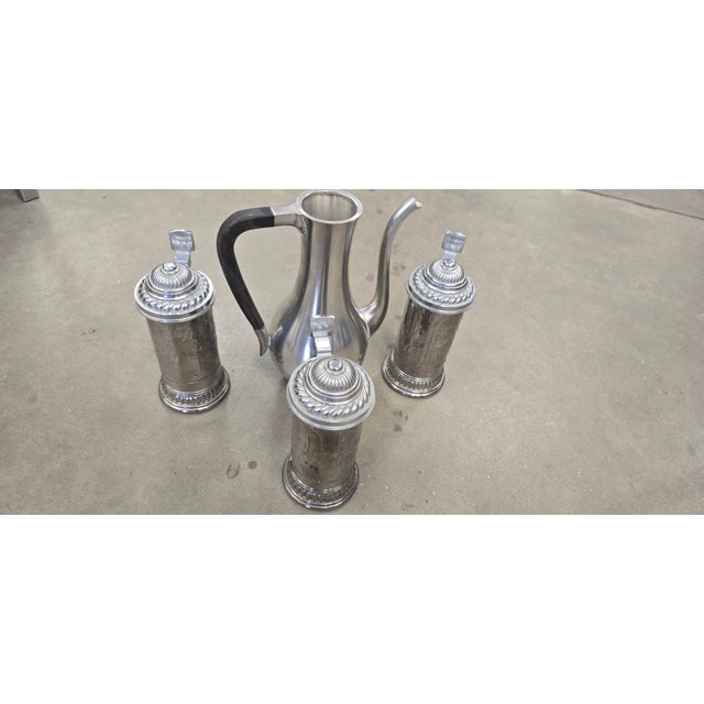 Offered is a striking vintage silver-plated set featuring a large handled pitcher and two matching lidded tankards/steins....