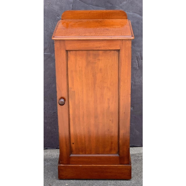 A handsome English nightstand or end (side) table of mahogany, with moulded top and gallery back over a cabinet door,...