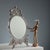 Table mirror with leafy scrollwork and cherub decorations. Oval beveled mirror. This piece is attributed to the mentioned...