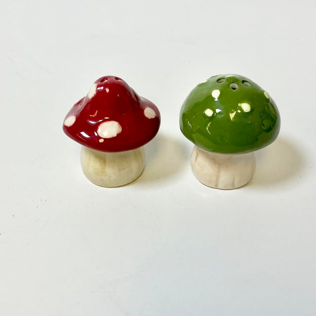 These are in very good vintage condition. The pair of ceramic mushroom salt and pepper shakers. One has a red top with...