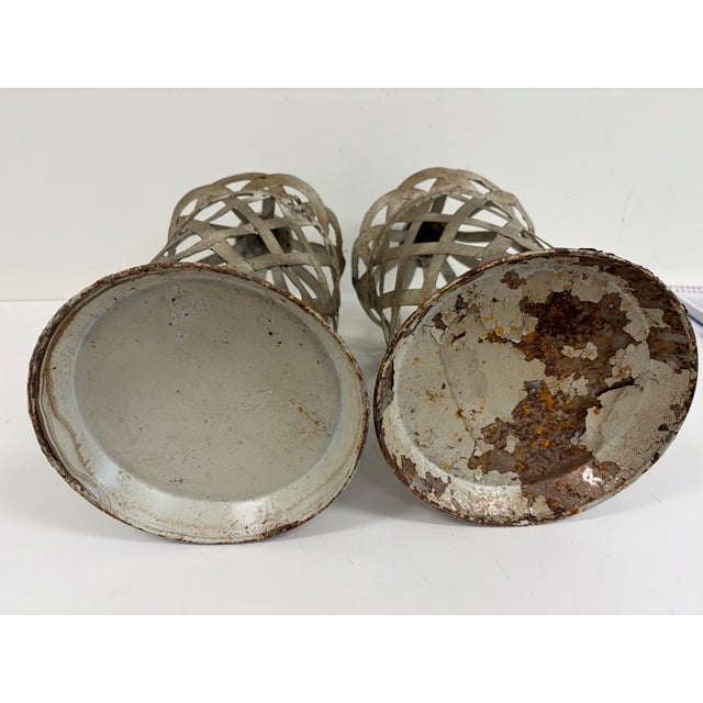 Pair of decorative metal lanterns with open lattice sides, domed tops, and distressed painted finish. Tall cylindrical...