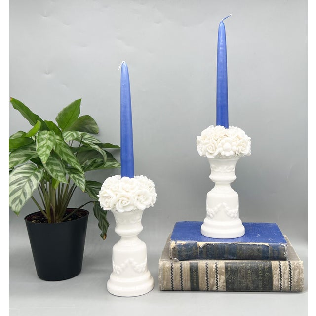 Exquisite pair of white glazed porcelain candlestick holders featuring intricately applied floral bouquet tops. Each is...