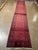Vintage Hand-knotted Afghan runner with repeating rows of small octagonal Bokhara guls on a red field and dark navy...