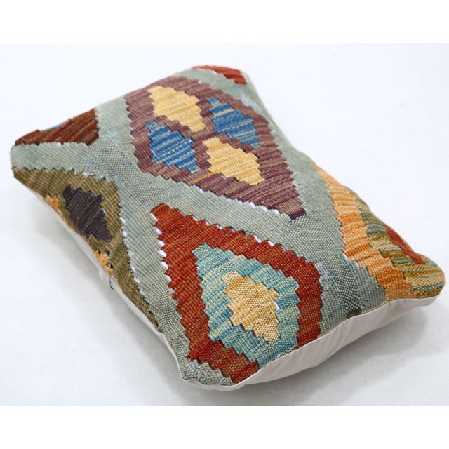 A one-of-a-kind handwoven Afghan wool kilim lumbar pillow featuring diamond medallions on a sage ground. Cut and sewn by...