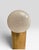 This lamp is a sleek brass cylinder column with a white bulb. Unsure of the designer. The cord looks to be from the 60s....