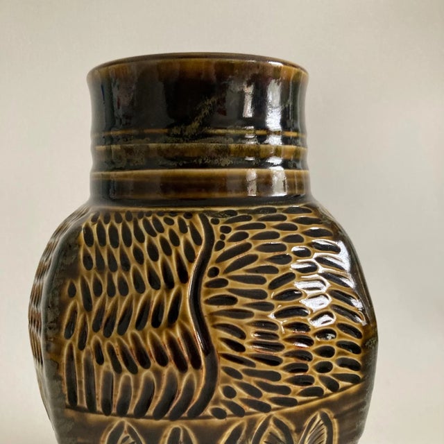 A stunning and solid studio pottery vase in a deep greenish/brown glossy glaze with lighter color accenting the incised,...