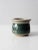 This is a vintage studio pottery jar. The hand-crafted ceramic jar features a green and speckled oatmeal glaze. An etched...