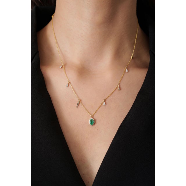 This station charm necklace features a 0.45 carat oval cut emerald set in 14K yellow gold. The emerald measuring...