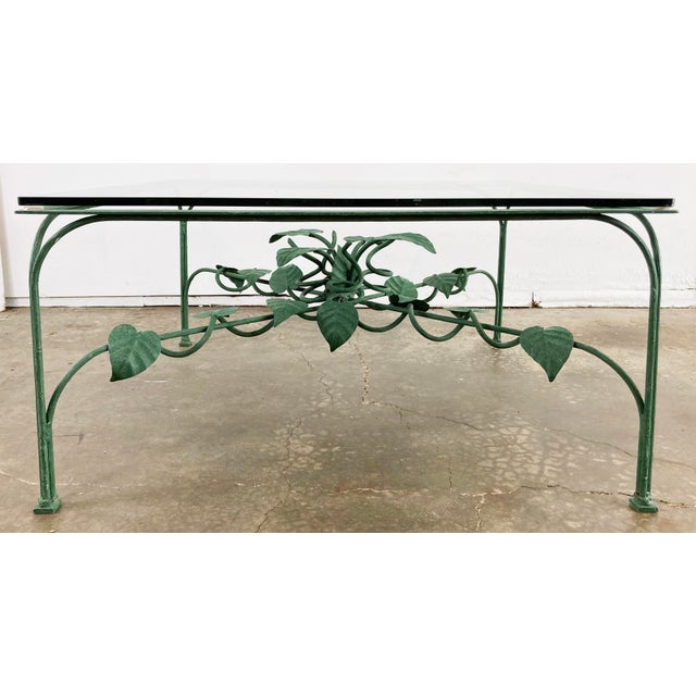 Vintage iron coffee table with ivy vine motif to base. Vining leaves central to base creep out support bars to legs...