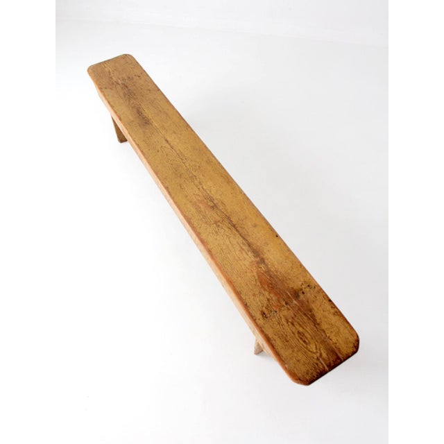 An antique farmhouse bench with a wonderfully timeworn surface and a long, generous silhouette that makes an immediate...