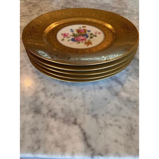 Exquisite vintage Limoges dinner plates featuring a richly detailed floral motif at the center, elegantly framed by a...