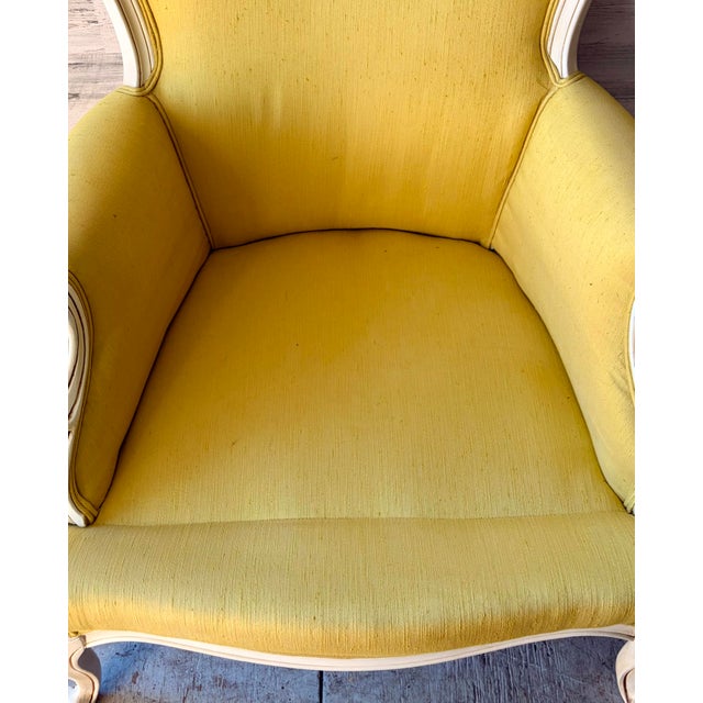 Vintage French Louis XV style bergere armchair. Chartreuse yellow with white wood. carved detail on the arms, legs, and...