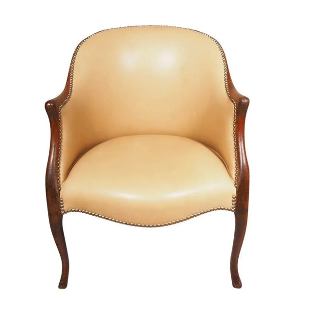 George III Mahogany Bergere Chair with an arched back and serpentine seat upholstered in tan leather with brass tacks....