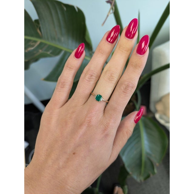 A Colombian emerald glows in vivid, slightly bluish green at the centre of this solid 14K yellow gold ring, flanked by two...