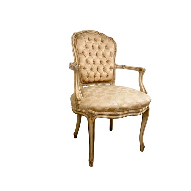 An elegant vintage French Provincial armchair inspired by the fluid forms of Louis XV seating, featuring a carved painted...