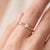 A soft, romantic solitaire featuring a blush pink marquise-cut rose quartz set in an east-west orientation, held by a...