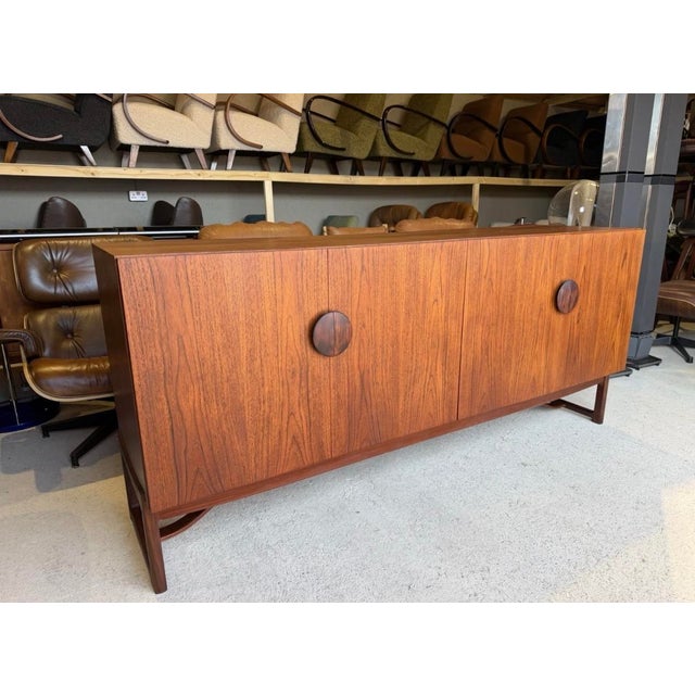 Distinguished by its long, simple lines and large, split circular handles, reminiscent of classical Chinese cabinet...