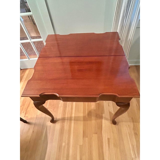This is a vintage flip-top game table crafted in the Queen Anne Revival style, featuring graceful cabriole legs, a richly...
