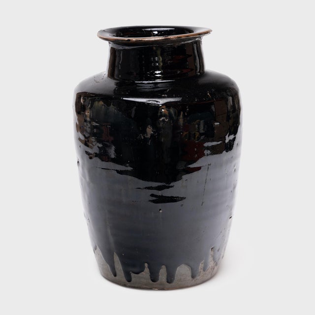 Cloaked inside and out with a glossy black glaze, this antique Chinese pickling pot was originally used for fermenting...