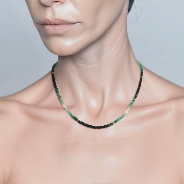 Emerald, graduated from deep green through pale mint to nearly clear. 18K gold beads spaced through the strand mark the...