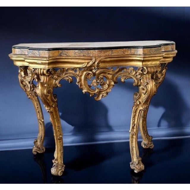 Roman mid-18th century gilt-wood Rococo consoles with a Yellow Siena veneered marble top within a black marble surround,...