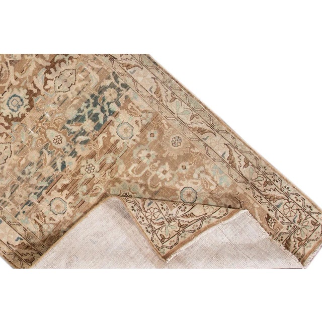 Beautiful antique Persian Hand-knotted wool runner with a beige field. This rug has brown and teal accents in a floral...