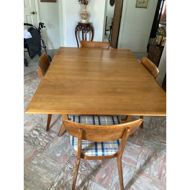 A 1950s mid-century modern Haywood-Wakefield drop-leaf dining table with 4 chairs is a classic example of American...