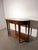 An elegant double-faced console table with a warm brown wood finish, rounded ends and slender legs. Finished on both...