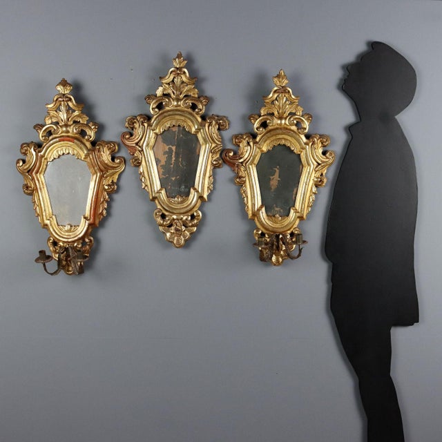 Set of three carved and gilded wooden mirrors. Molded frame embellished with leaf and scroll carvings, mercury mirrors,...